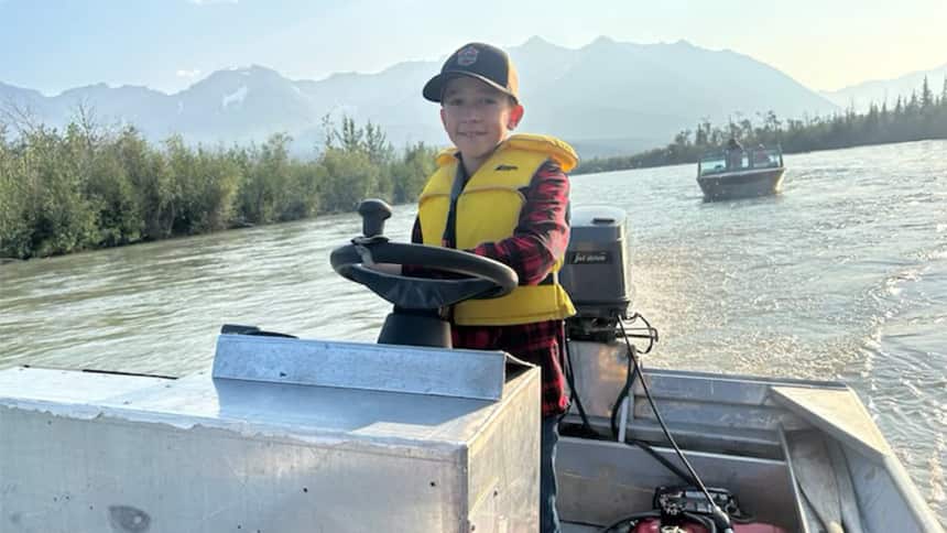 Image of Roy driving a boat wearing a life jacket. 