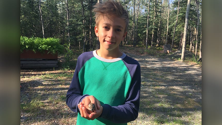 Roy standing outside holding a small bird in his hands.