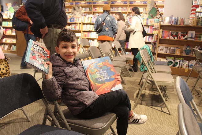 Rex Tulba, 6, holds up new finds from Books of Wonder bookstore in New York City. His parents lean into his current obsessions when buying books, like mythology or traveling.