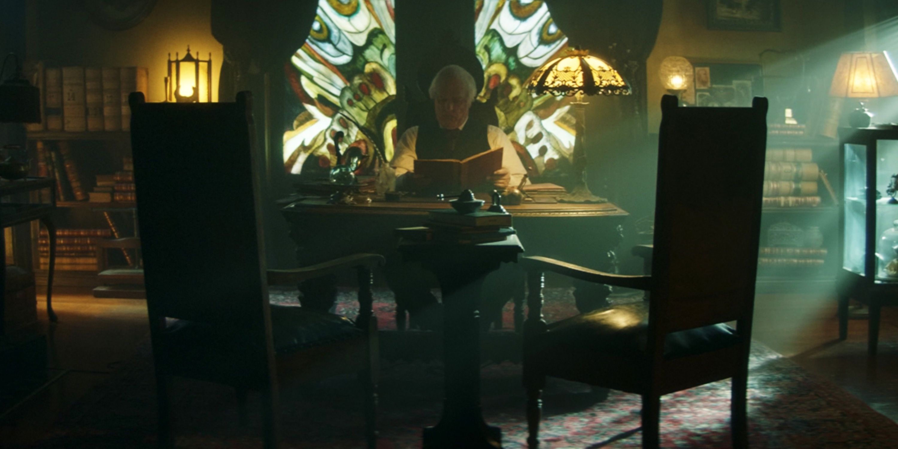Clancy Brown sitting at a desk in The Mortuary Collection