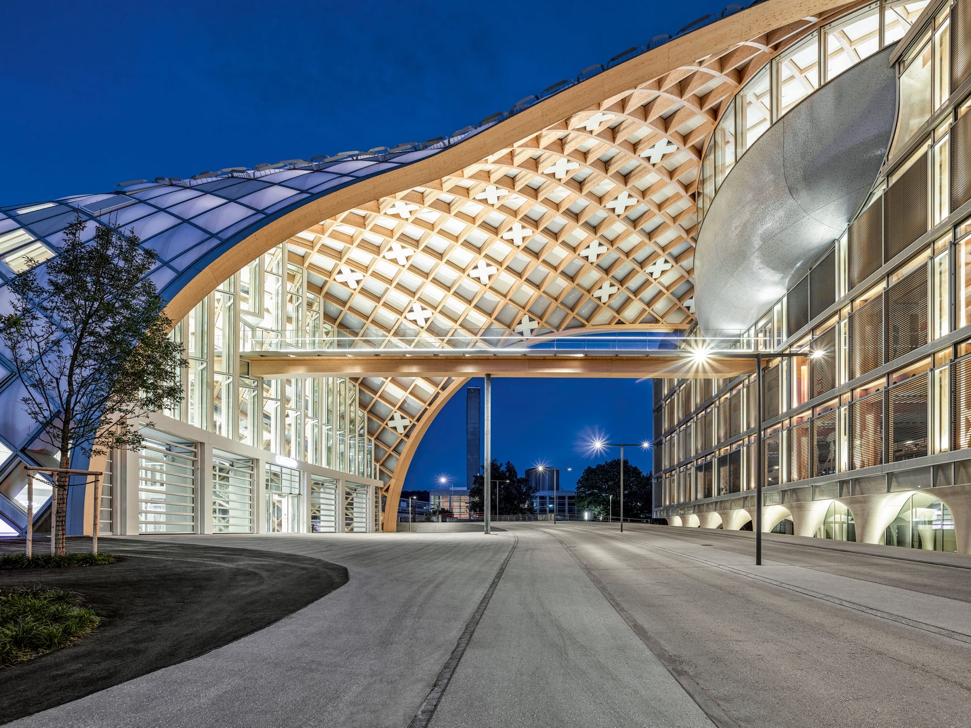 a large, architectural feature with intricate latticework curving over a road, photographed at night to show its illuminated underside