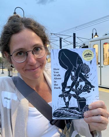 Erin Block holding her poetry book How You Walk Alone in the Dark
