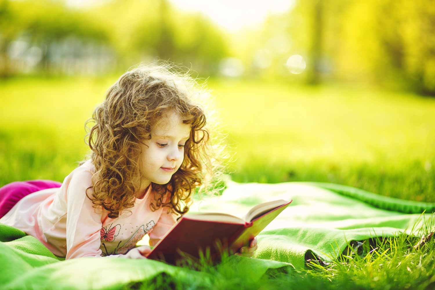 A girl sits with a book in a field - let literature inspire even a simple stroll with my top days out with kids who love books